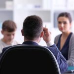 Young woman with son during teacher-parent meeting at school
